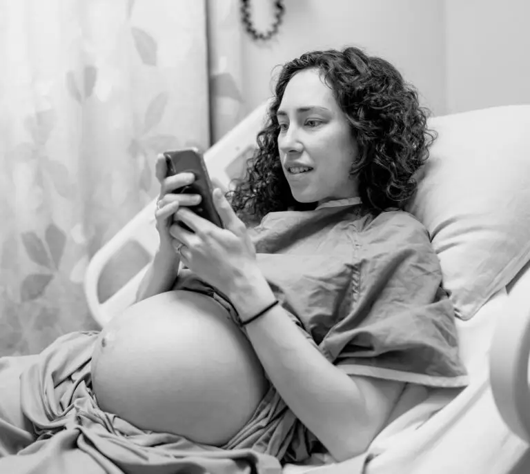 Pregnant person in hospital bed on a video call